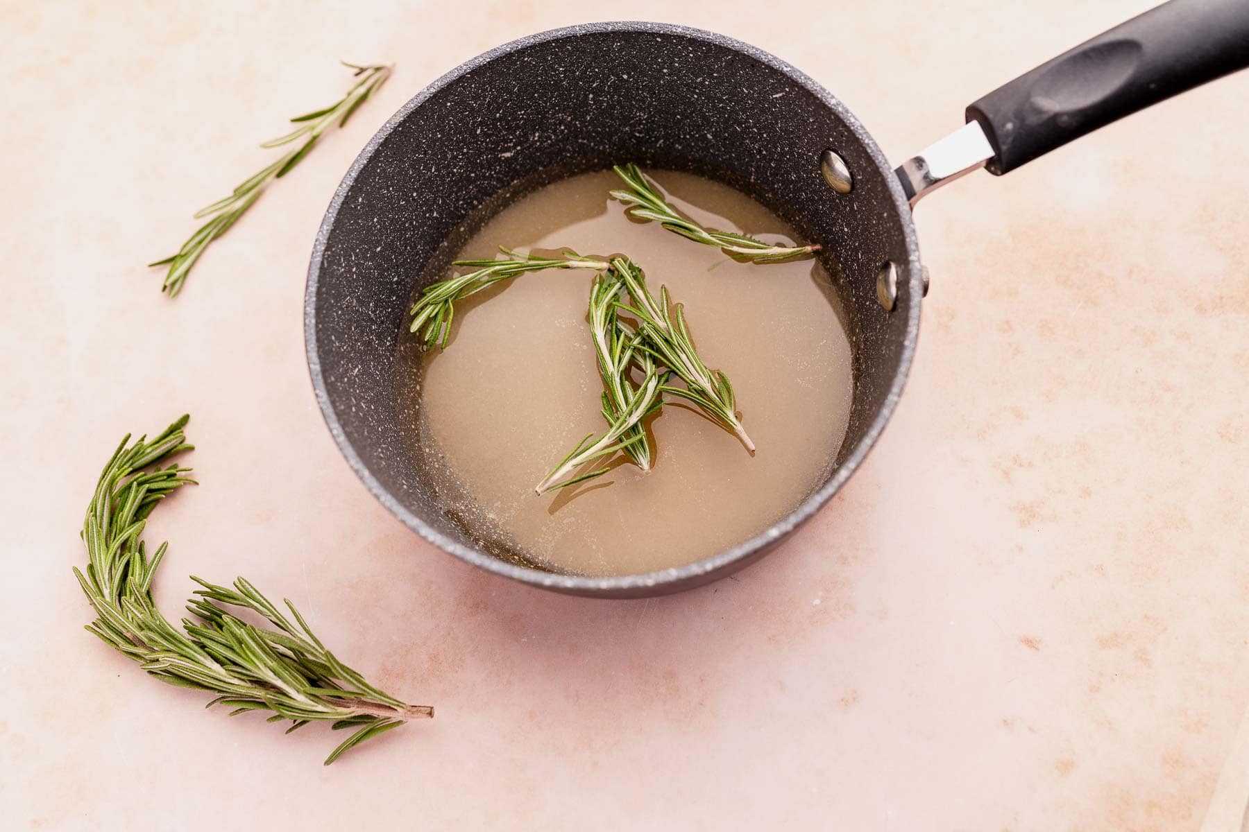 A pan with rosemary sprigs and rosemary simple syrup in it.