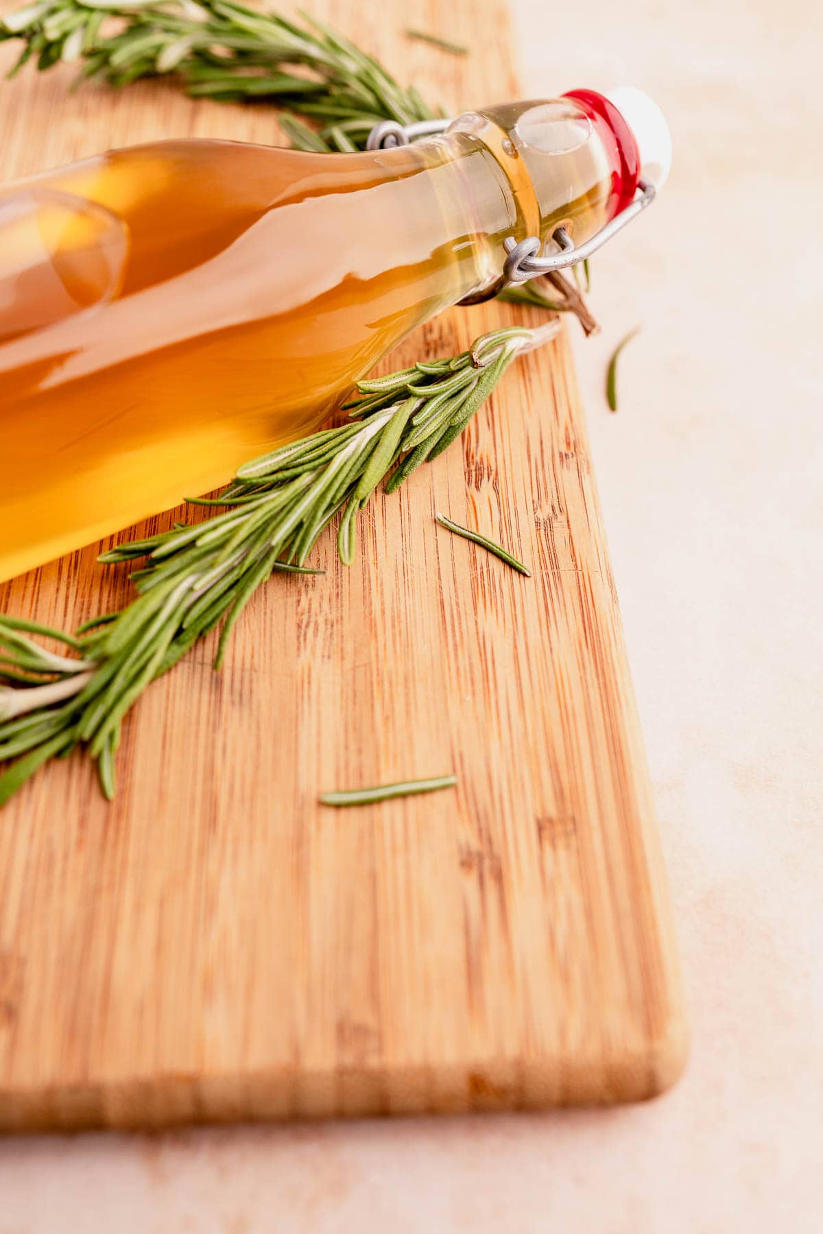 A bottle of rosemary-infused olive oil on a wooden cutting board.