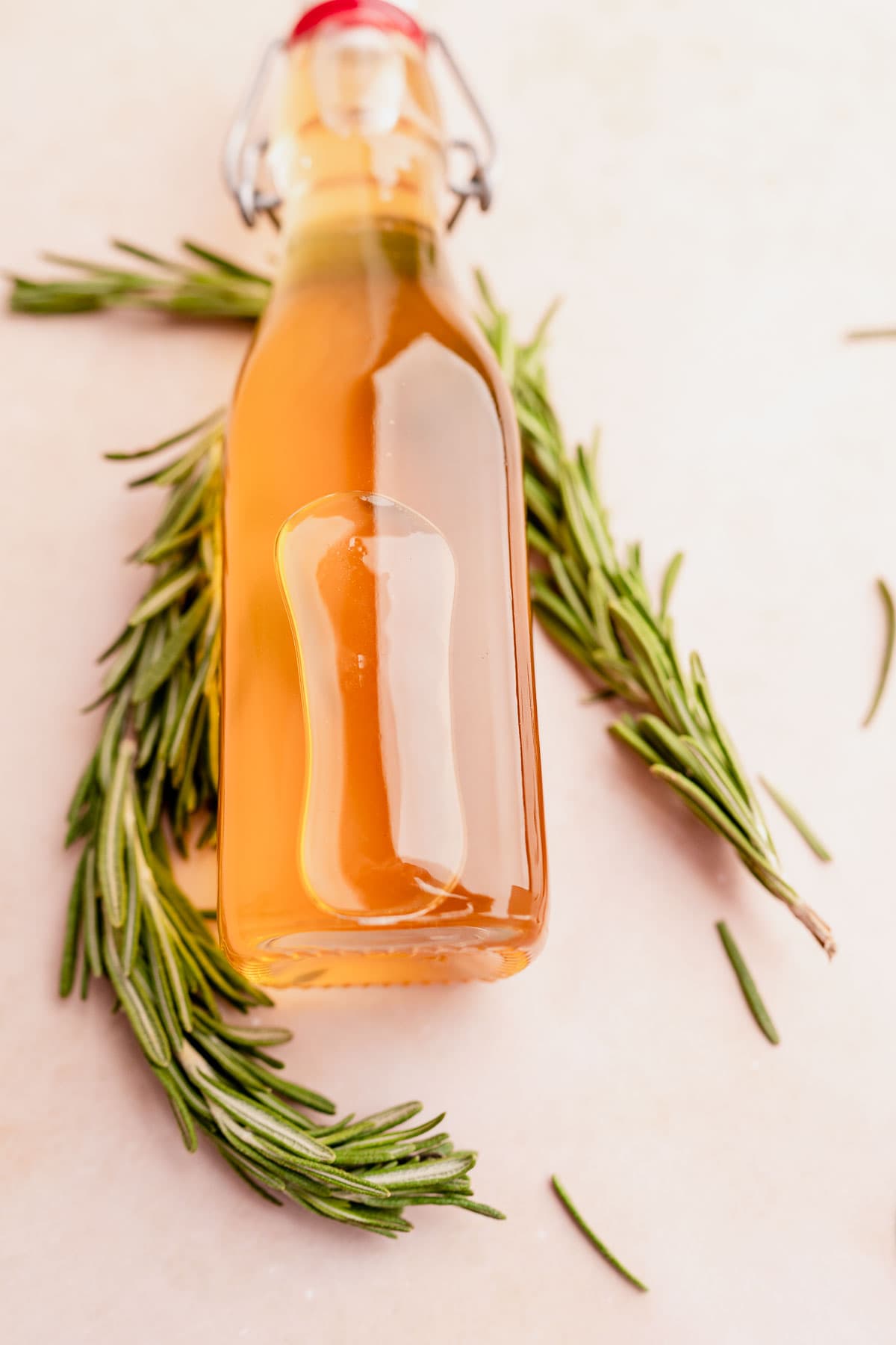 A bottle of rosemary simple syrup on a white background.