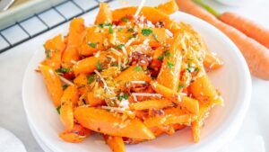 Roasted carrots in a white bowl with parmesan cheese.