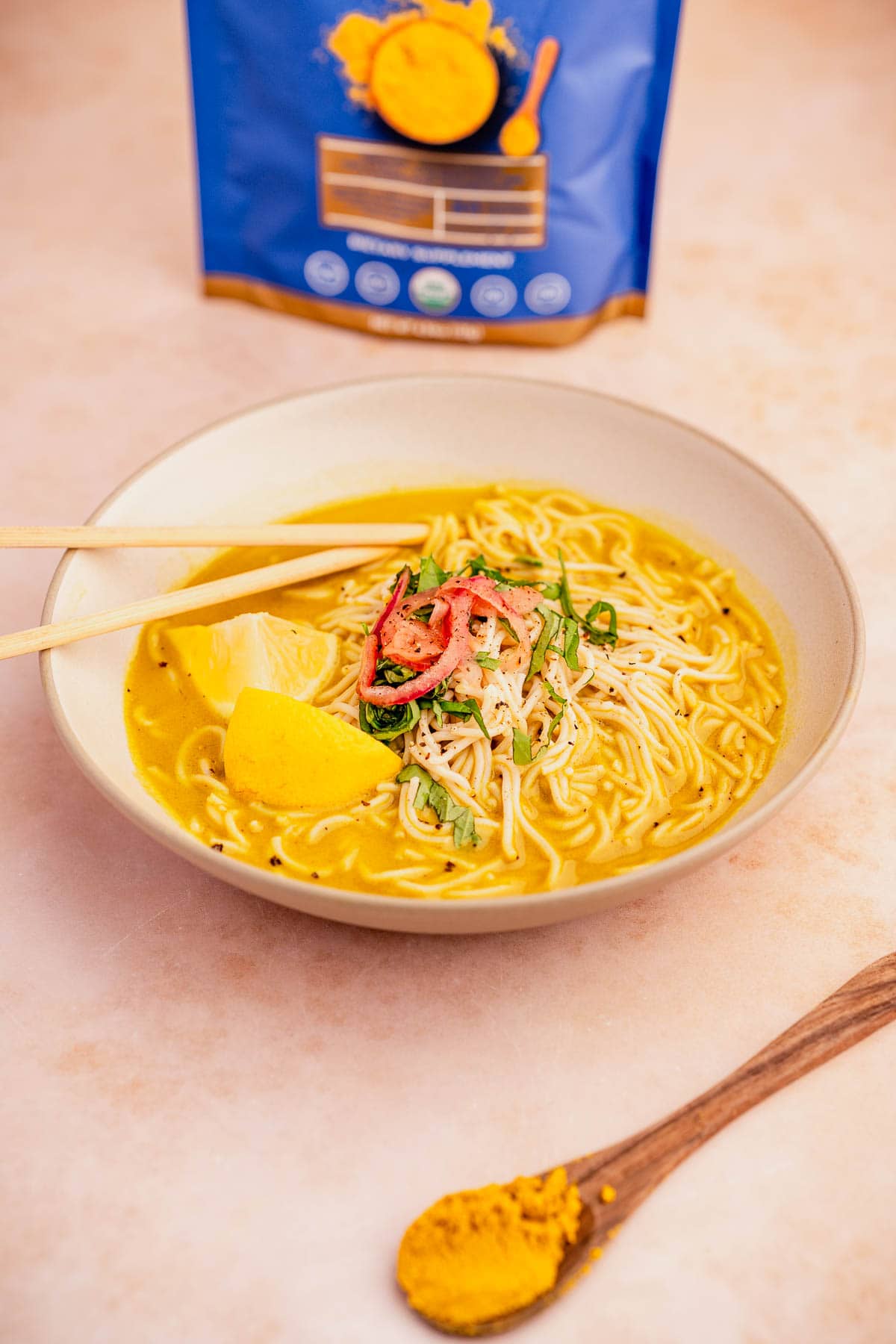 A bowl of golden noodles served with chopsticks.
