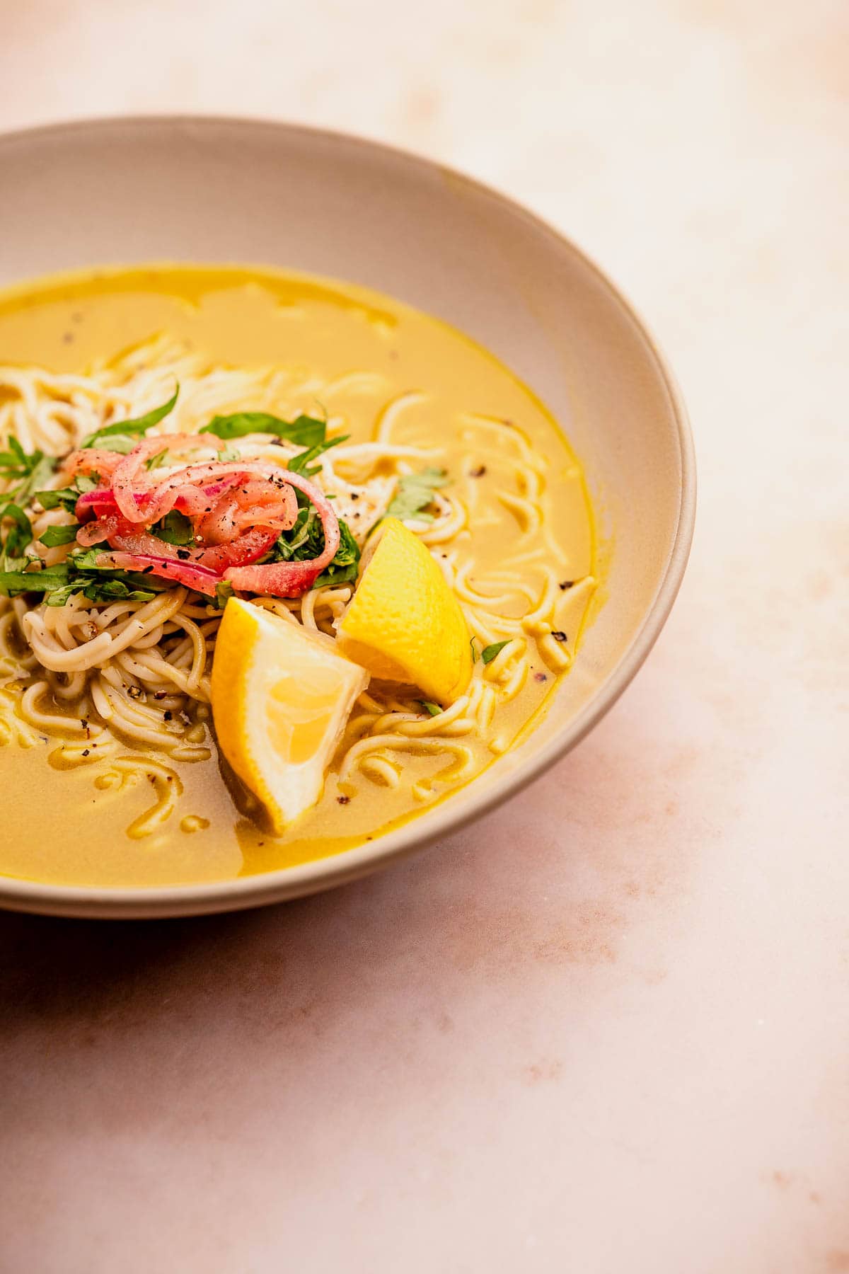 A bowl of golden noodle soup on a table.