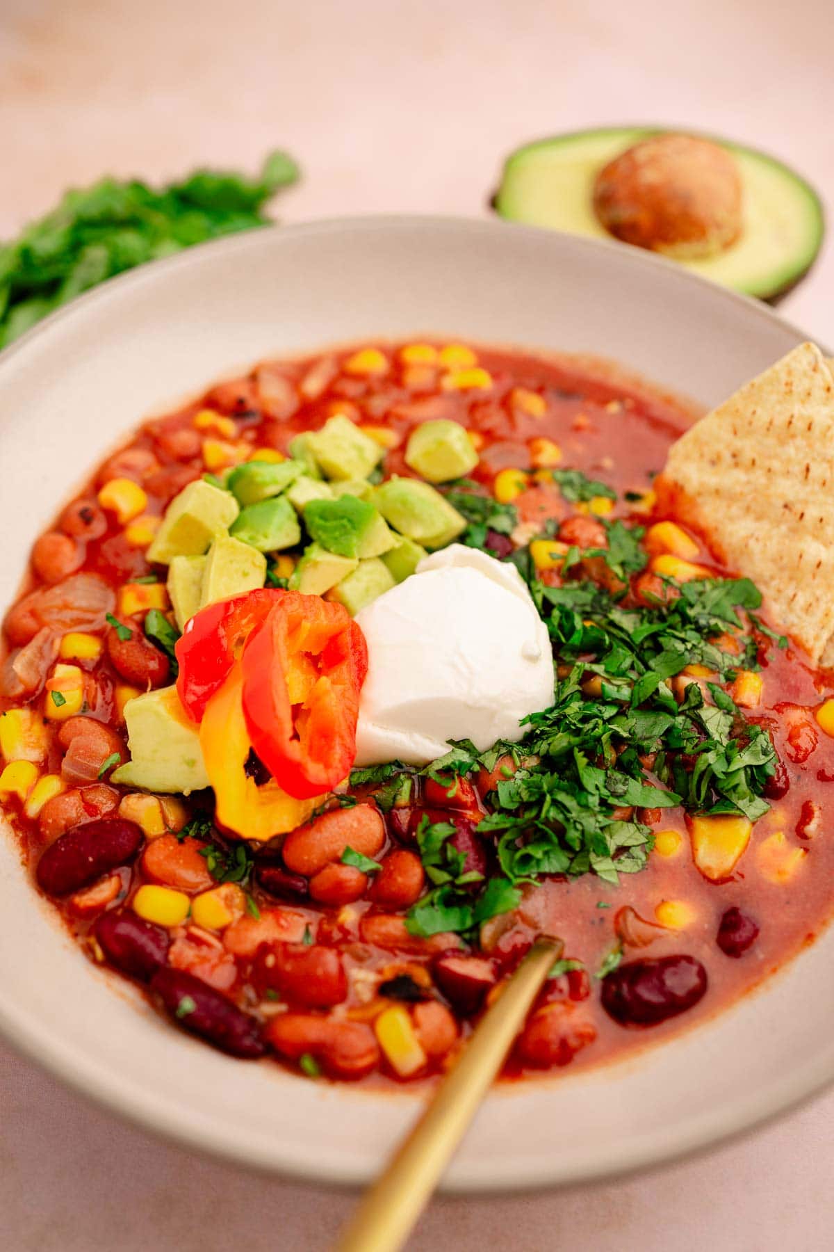 A bowl of slow cooker vegetarian chili with sour cream and avocado.