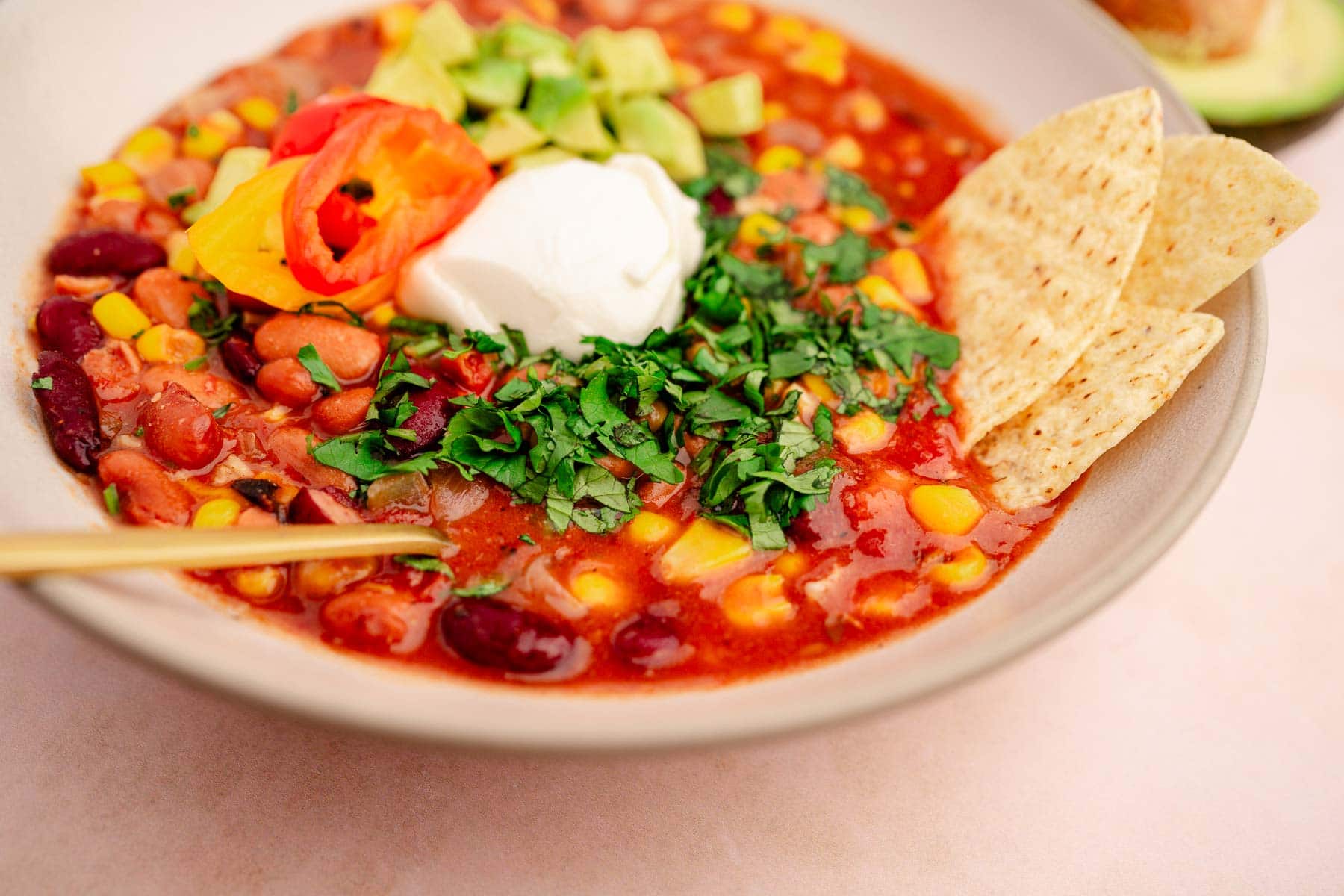 A hearty bowl of slow cooker vegetarian chili with beans, corn, sour cream, and avocado.
