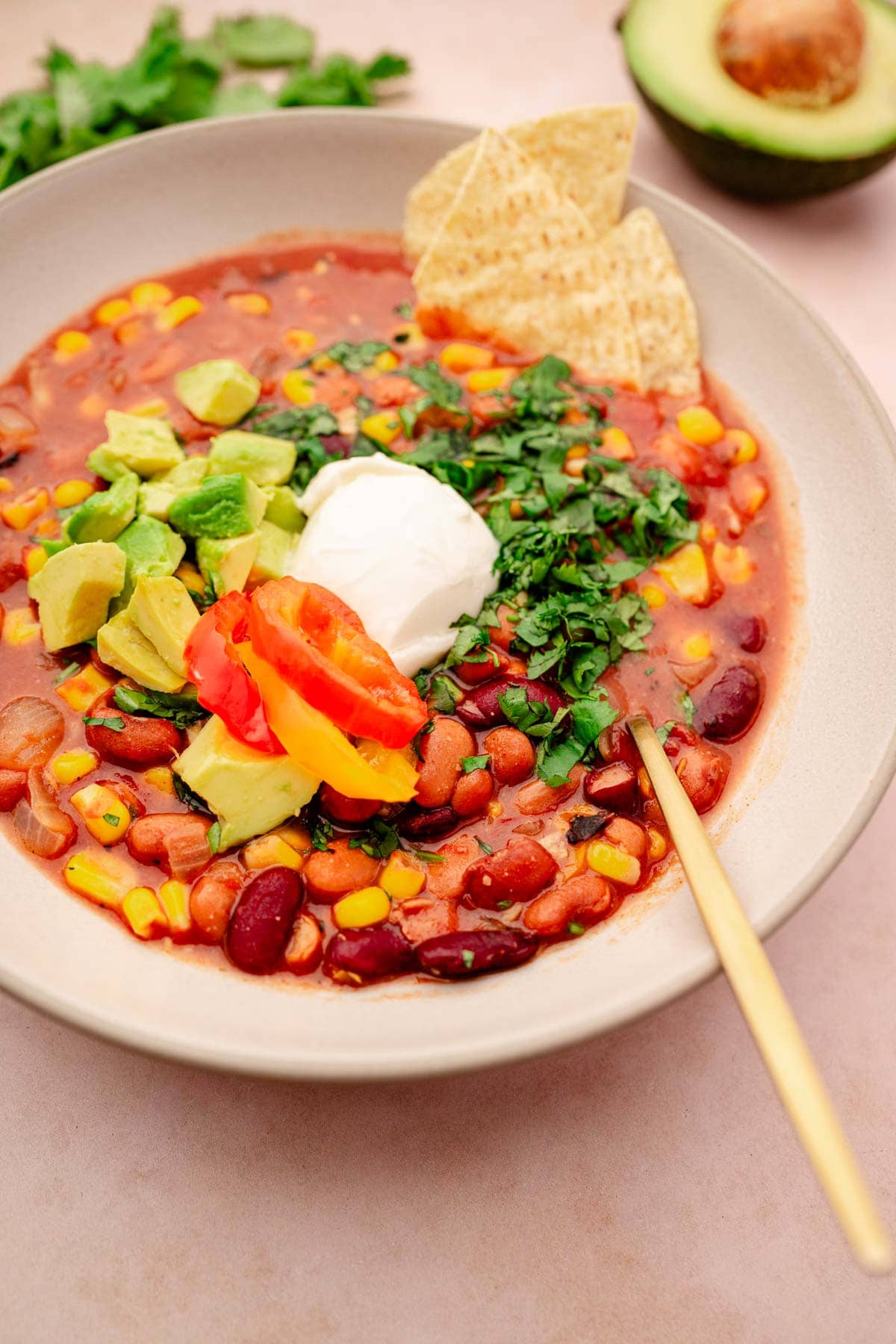 A slow cooker vegetarian chili with mexican beans, avocado, and sour cream.