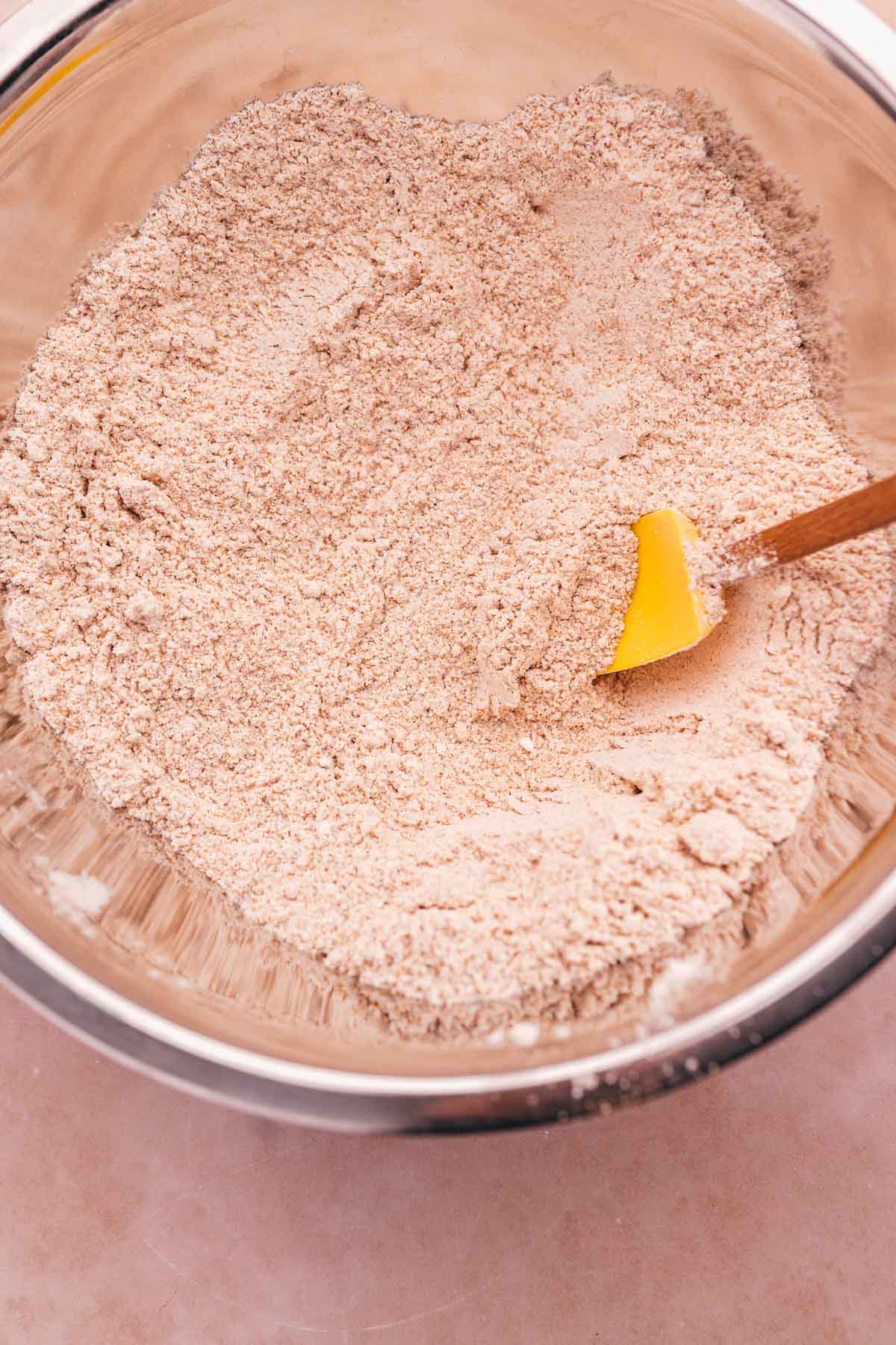 A bowl of gluten-free flour with a yellow spatula in it.