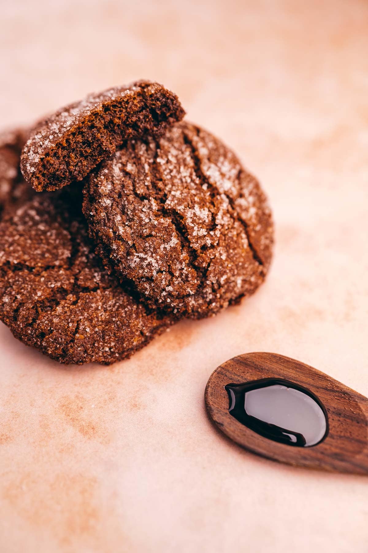 A pile of gluten free molasses cookies and a wooden spoon on a table.