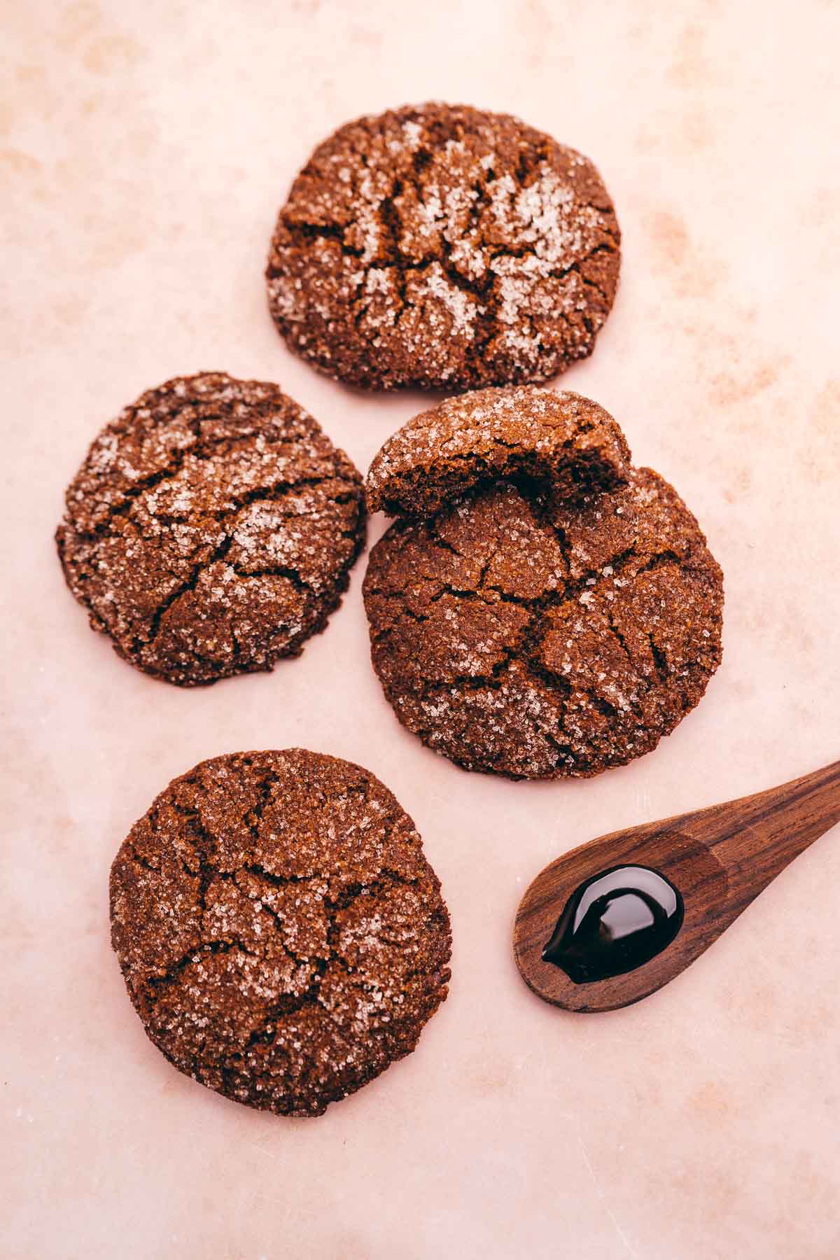 Four gluten-free ginger molasses cookies with a spoon on a table.
