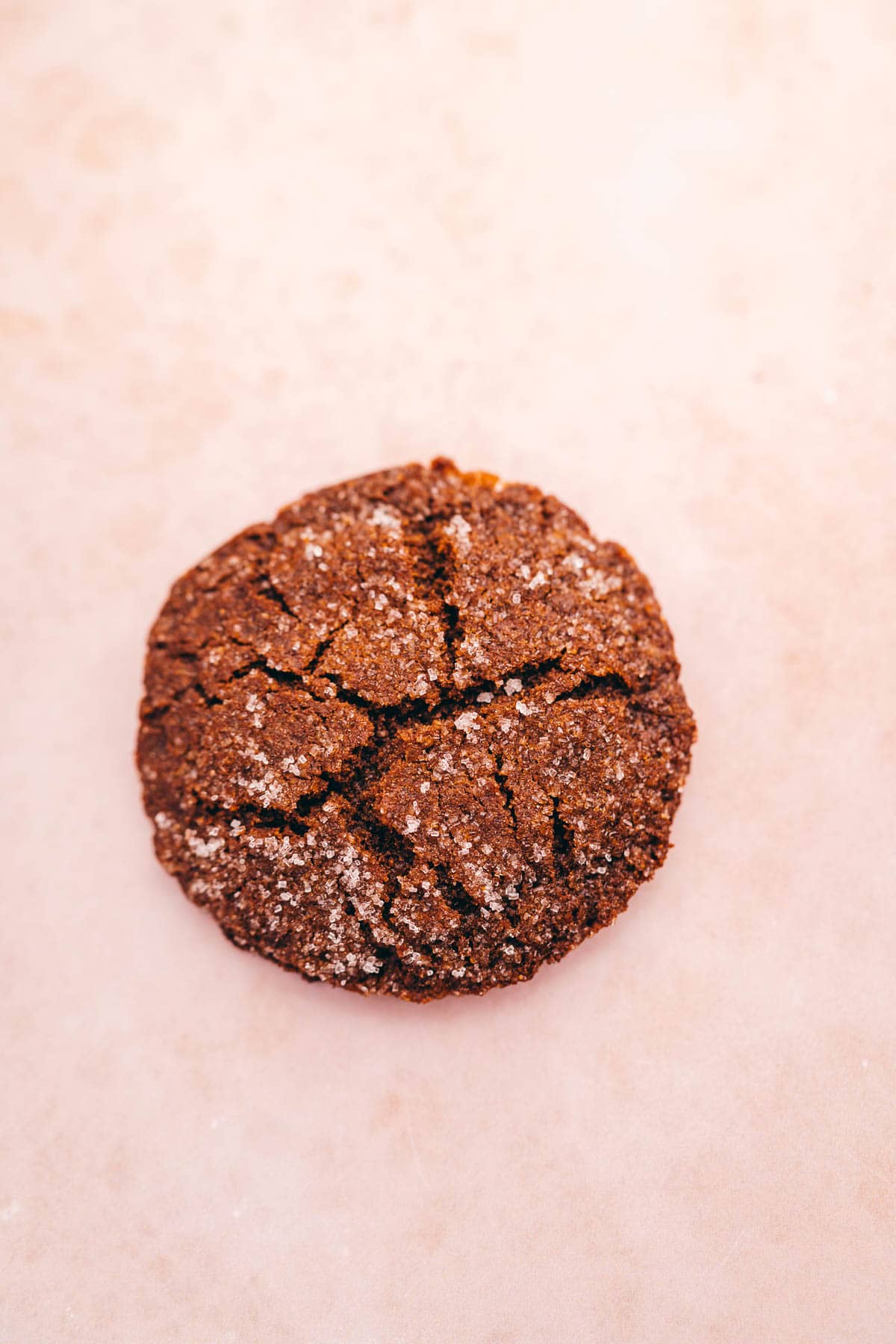 A gluten-free cookie is sitting on top of a pink surface.