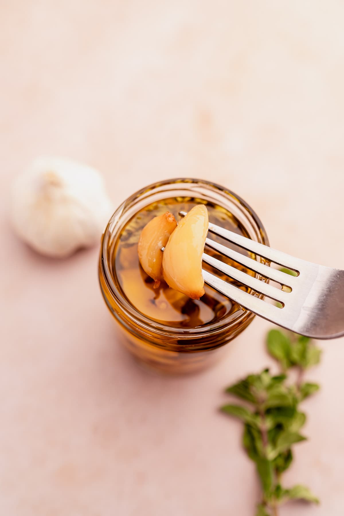 A jar of garlic confit with a fork on a table.