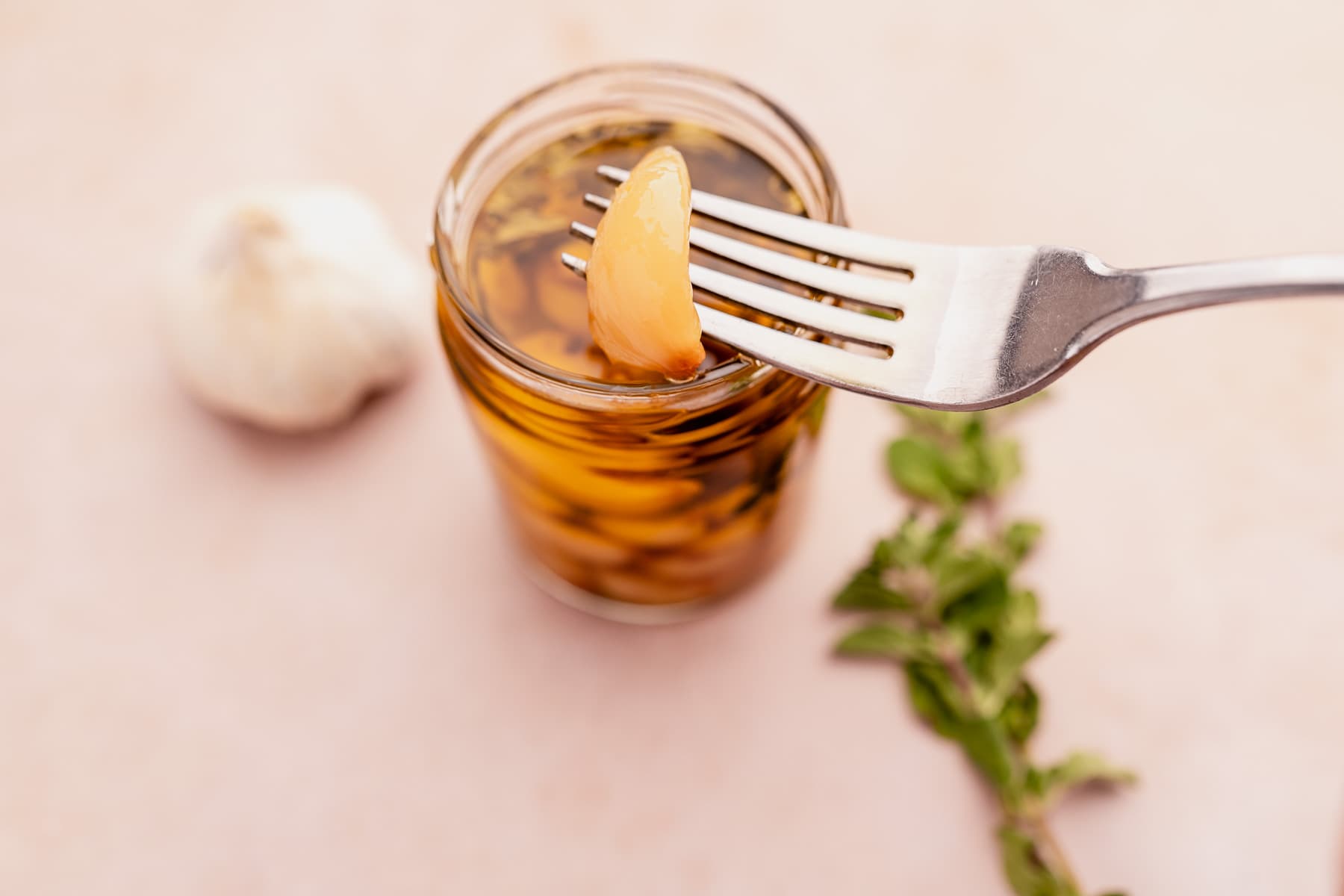 A fork is delicately holding a jar of garlic confit.