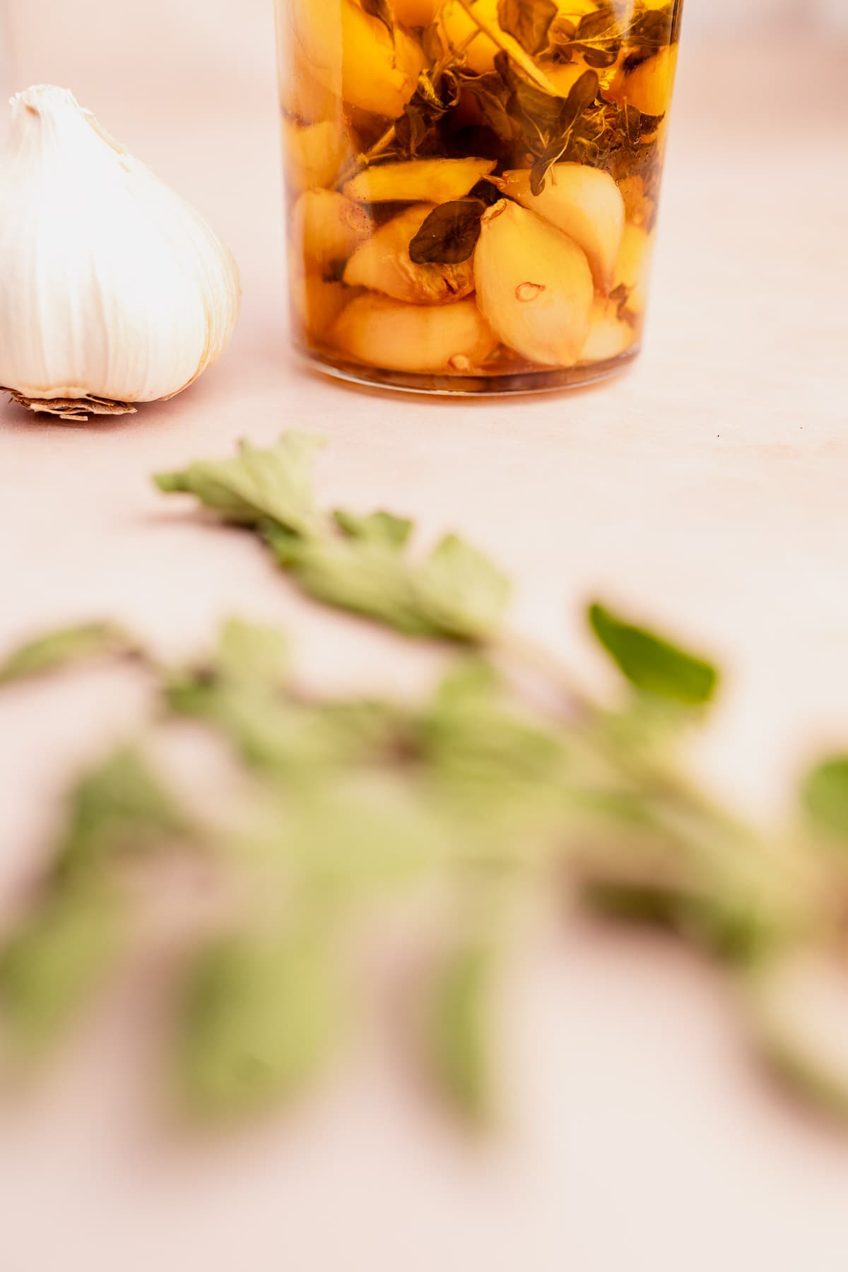 A jar of garlic confit and herbs on a table.