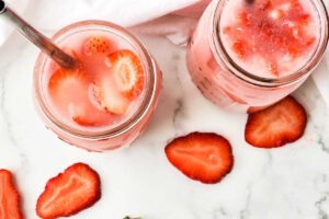 Two mason jars with strawberries in them.