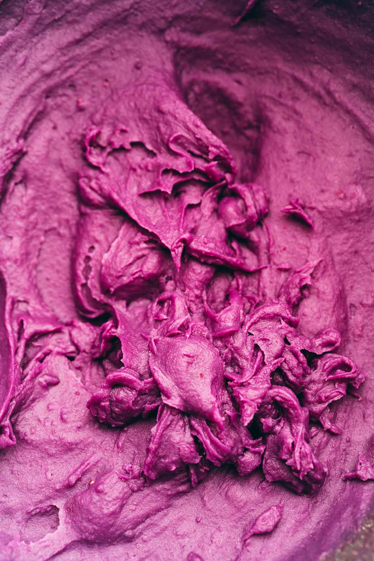 Mashed purple sweet potatoes in a bowl with purple icing on top.