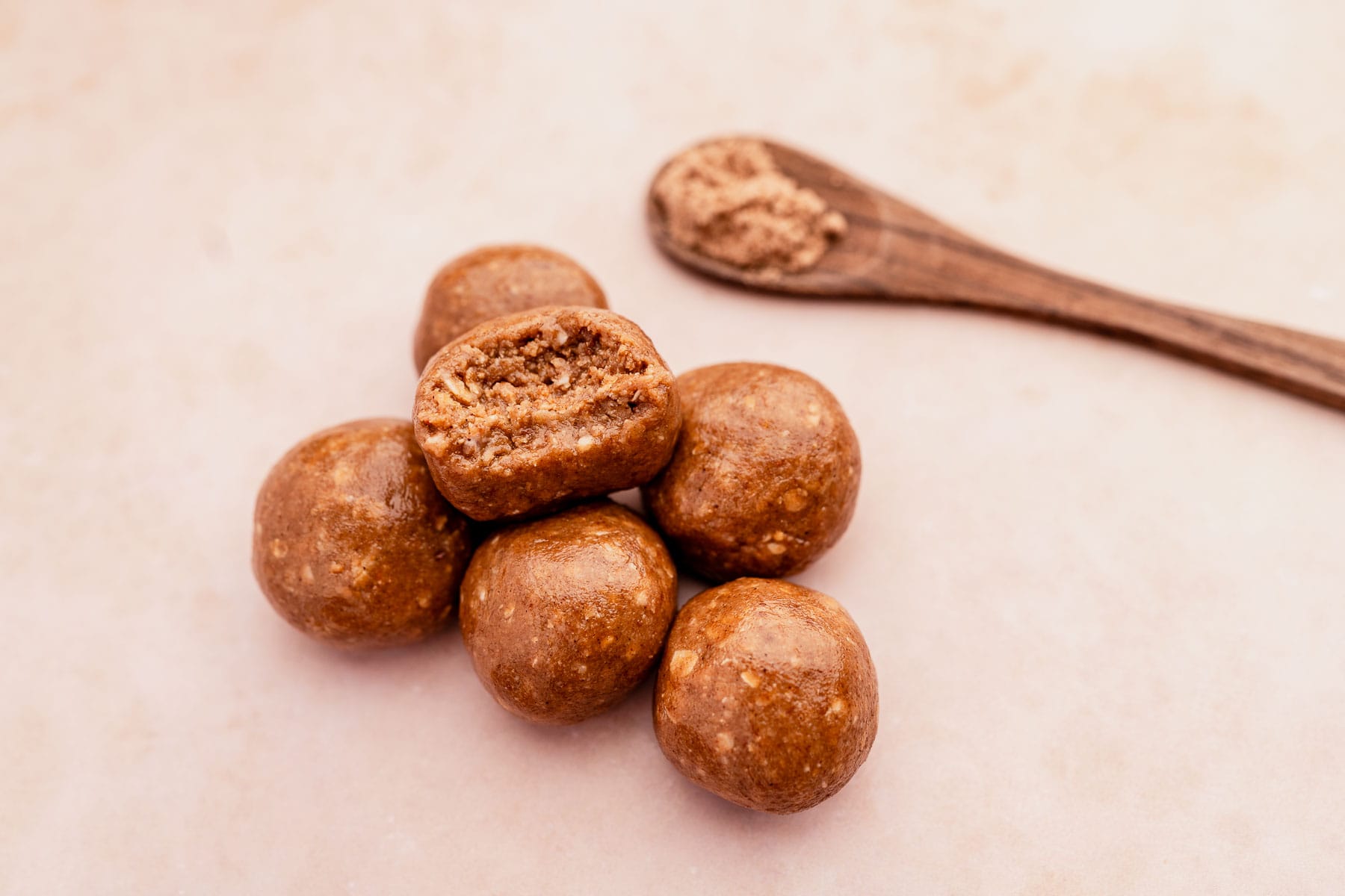 Chai energy bites on a white background with a wooden spoon.