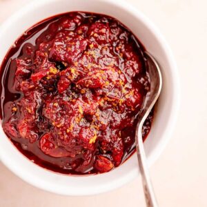 A slow cooker cranberry sauce with a spoon.