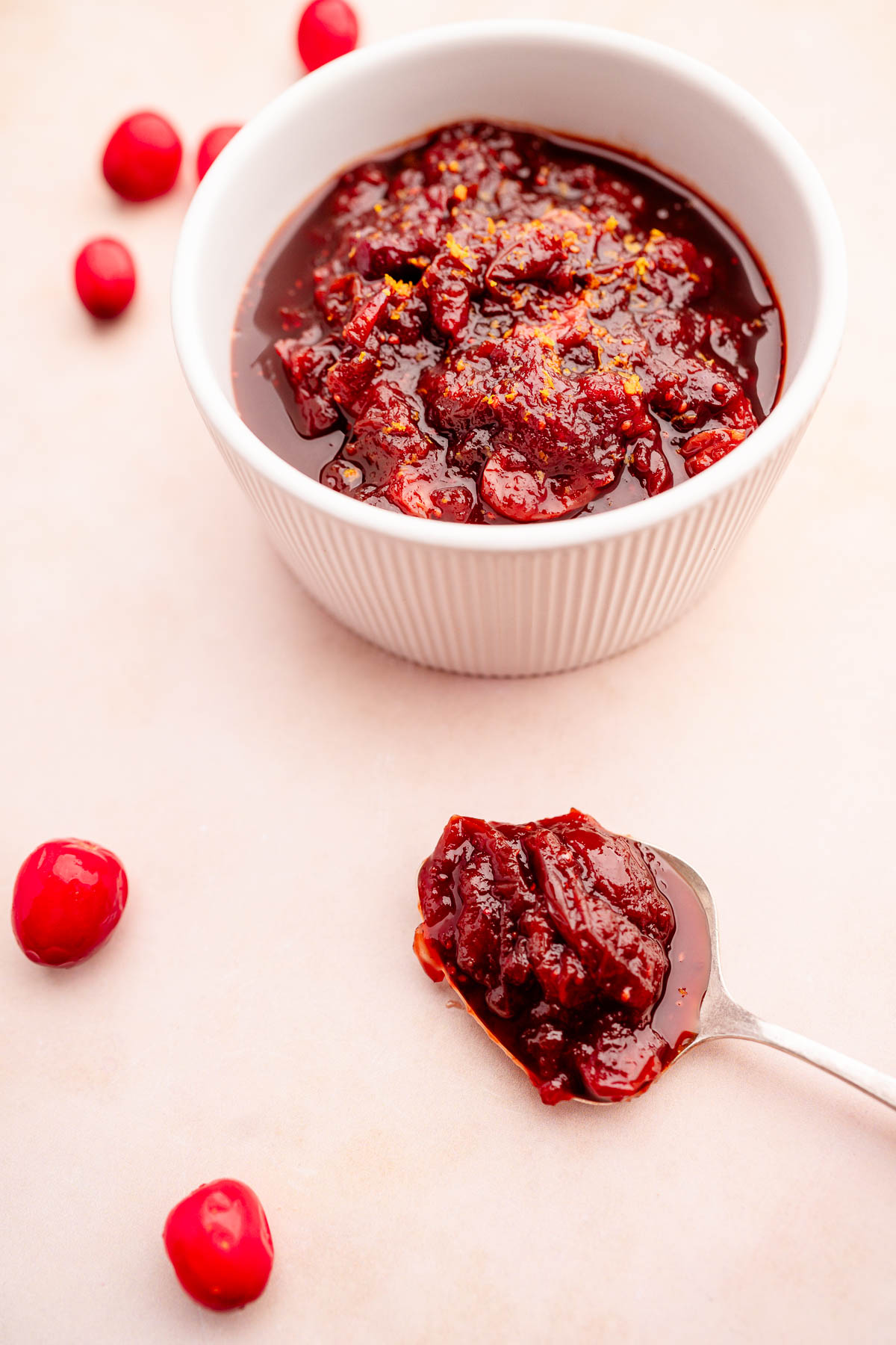 A bowl of slow cooker cranberry sauce next to a spoon.