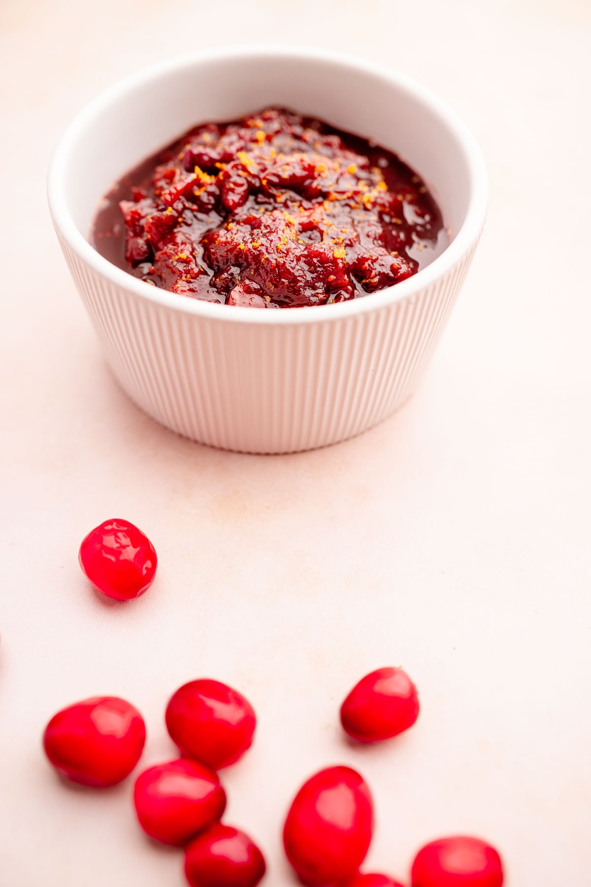 A slow cooker bowl of cranberry sauce surrounded by red berries.