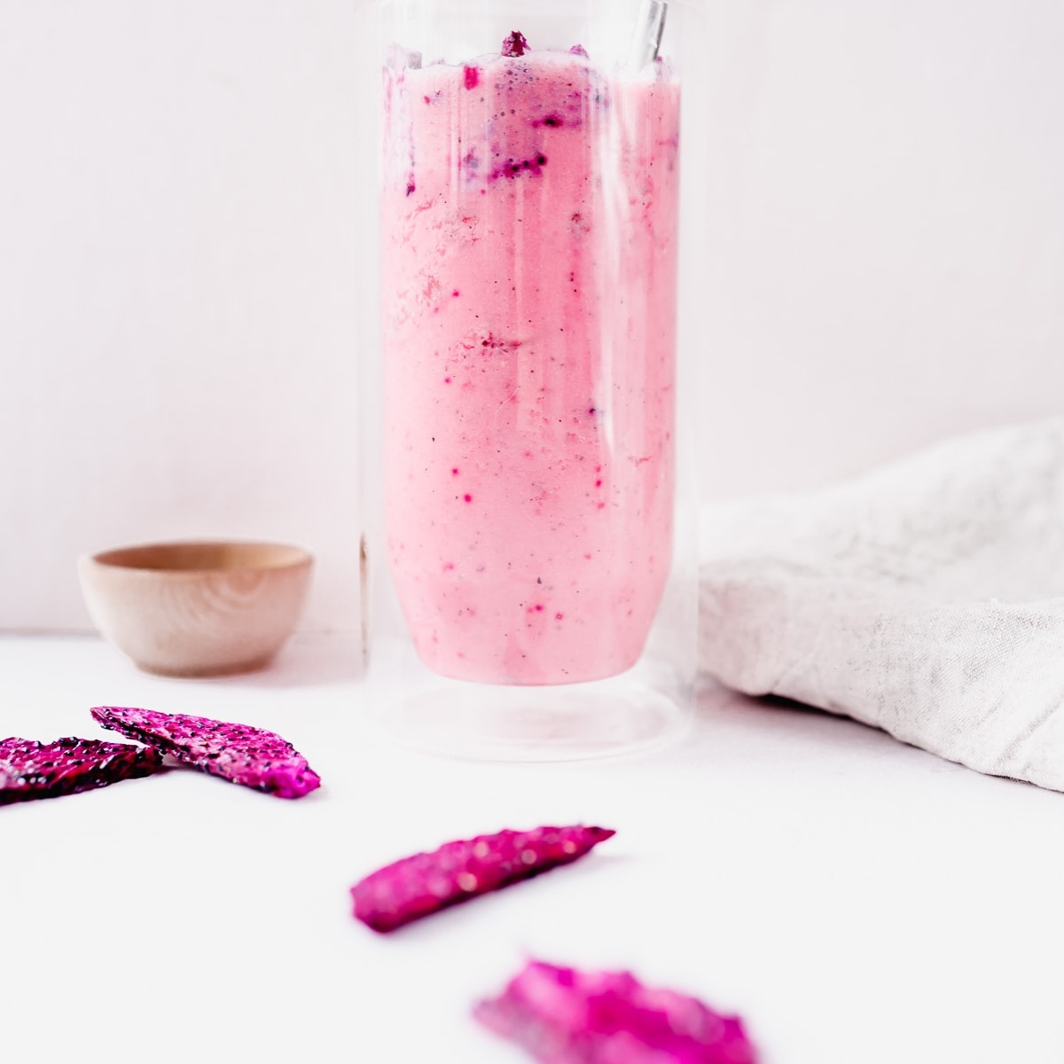 A pink smoothie in a glass with starbucks copycat drinks next to some pink chips.