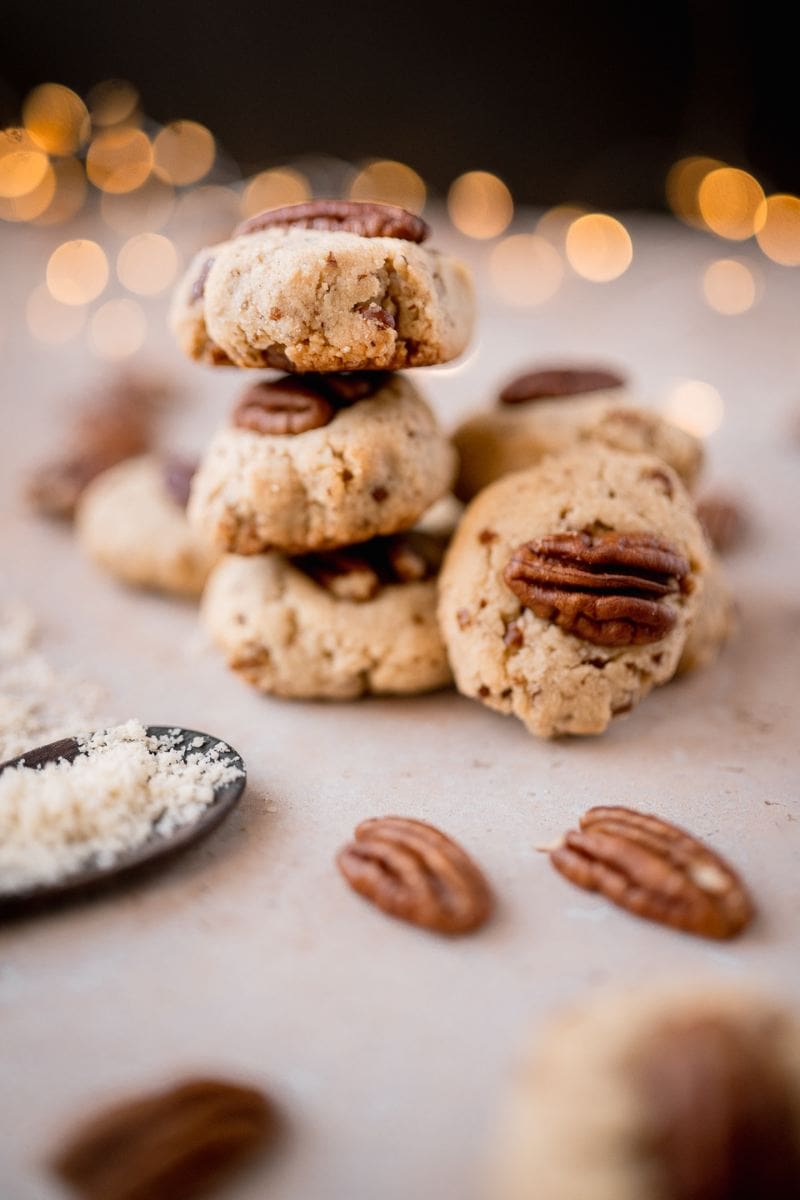 Gluten-free pecan cookies stacked on top of each other with a spoon.