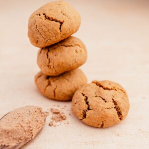 In this description, a stack of ginger chai cookies is placed next to a spoon and powder.