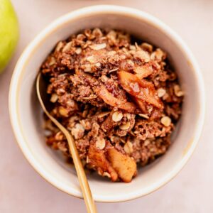 A gluten-free apple crisp made with a bowl of oatmeal, apples, and granola.