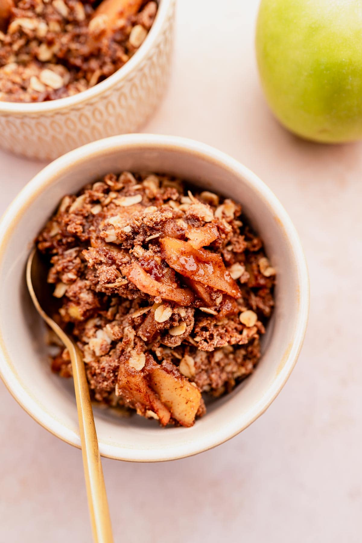 Gluten-free apple cinnamon granola in a bowl with a gold spoon.