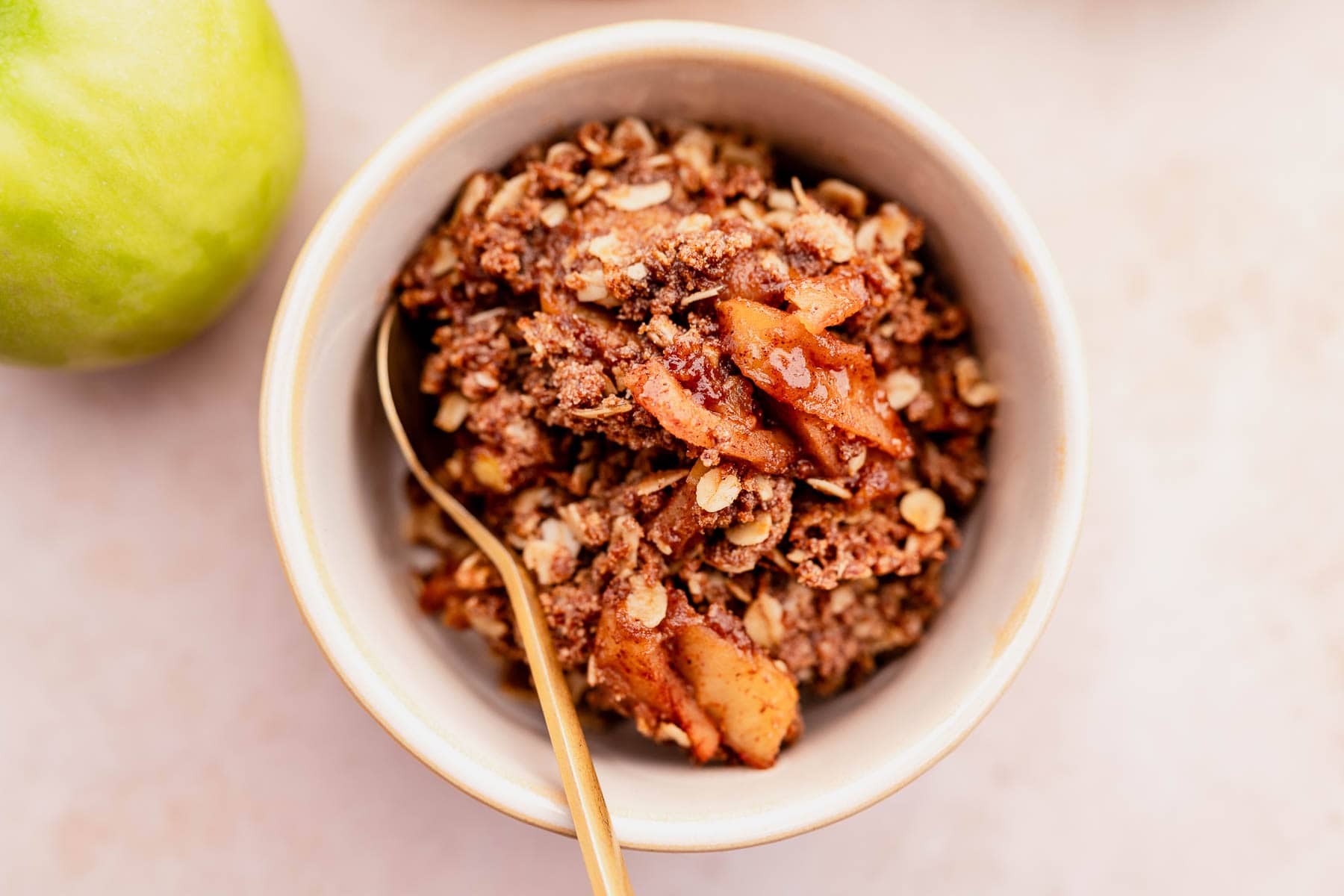 A bowl of gluten-free apple crisp granola with a gold spoon.