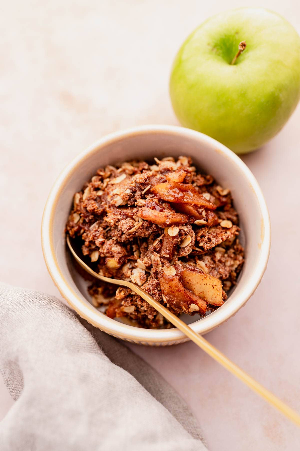 Gluten-free apple granola in a bowl with a gold spoon.