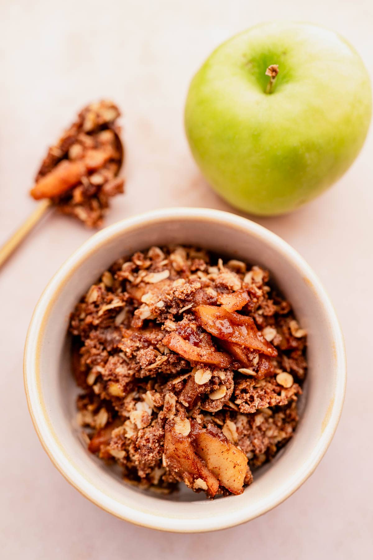 A gluten-free bowl of granola with fresh apples and a spoon.