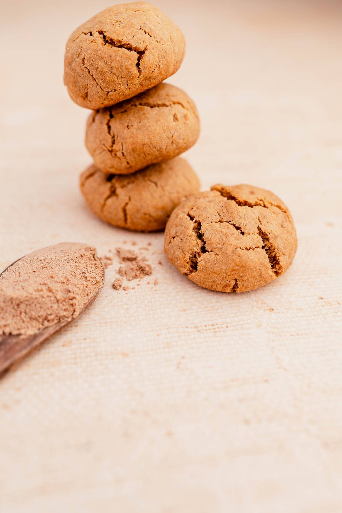 A stack of ginger cookies next to a wooden spoon.