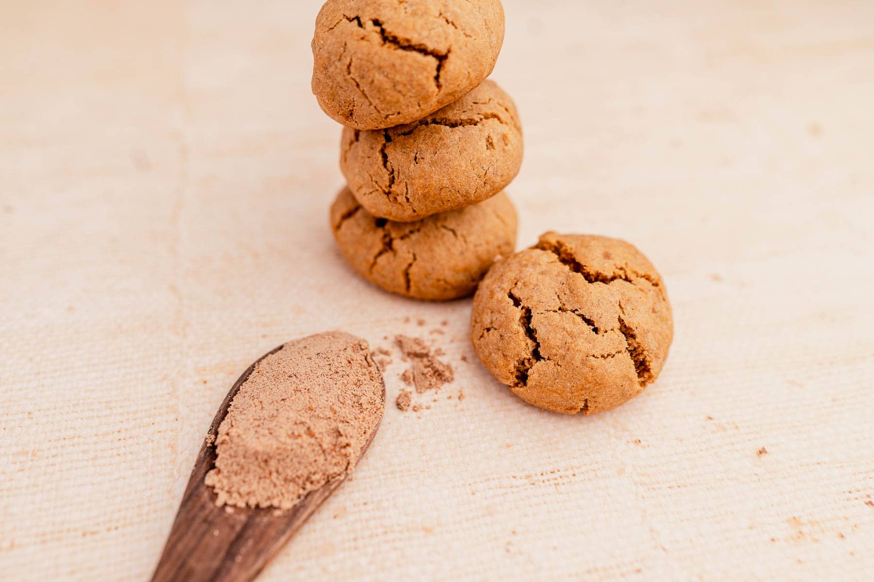 A stack of ginger chai cookies and a spoon with powder on it.