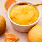 A bowl of vegan lemon curd with a spoon next to it.