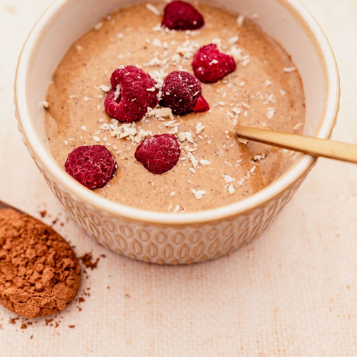 A bowl of blended chocolate chia pudding with raspberries.