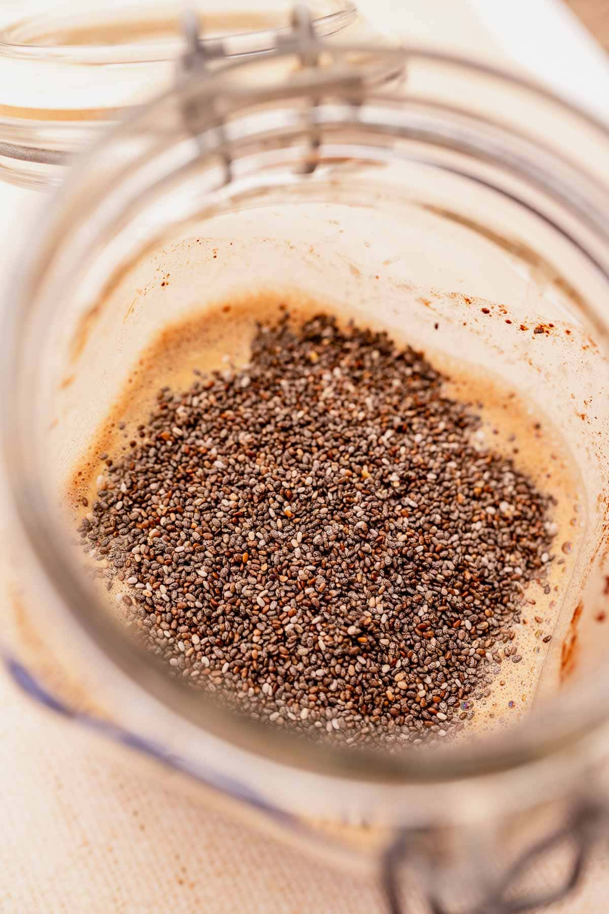 Blended chocolate chia pudding in a glass jar with chia seeds.