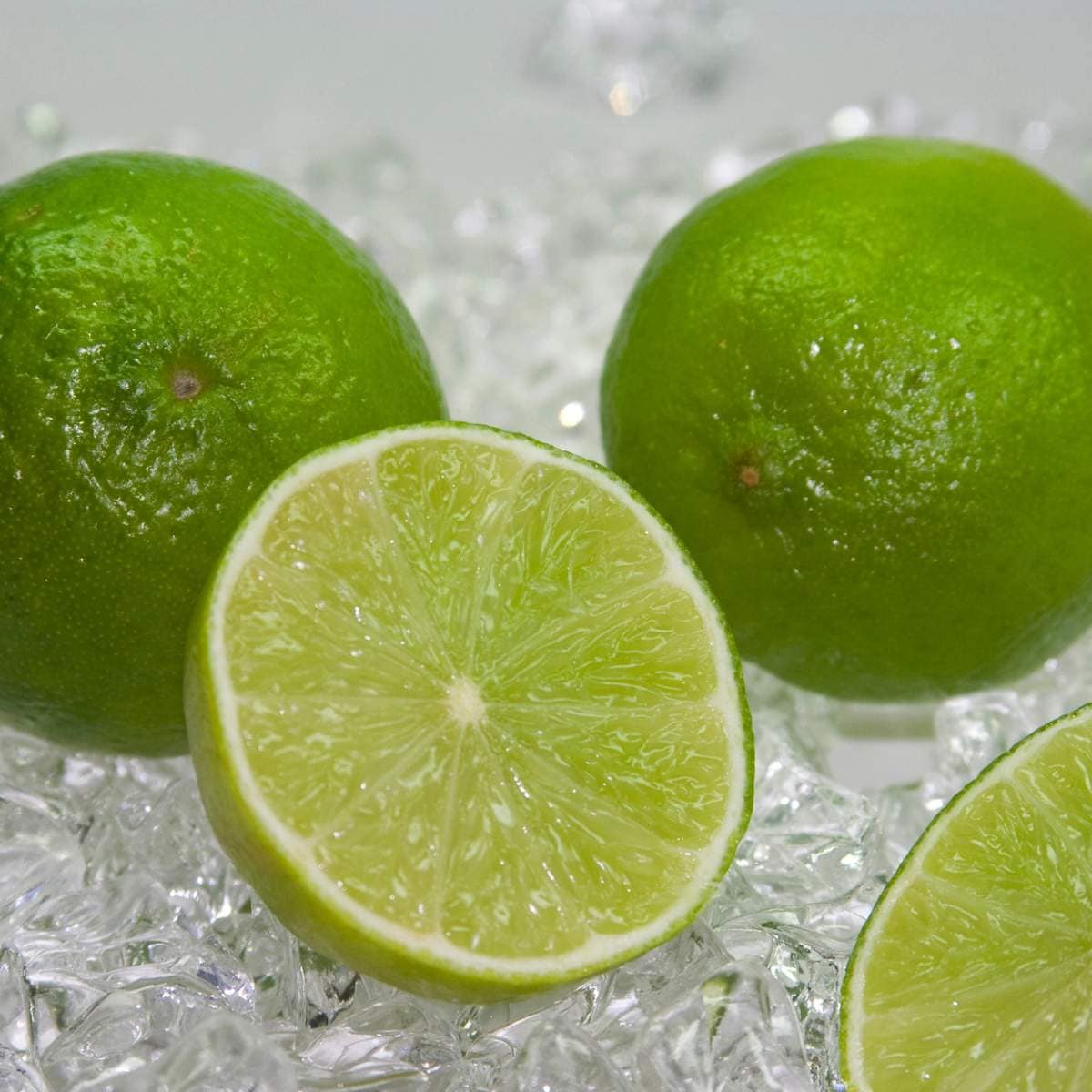 Three limes are sitting on top of ice.
