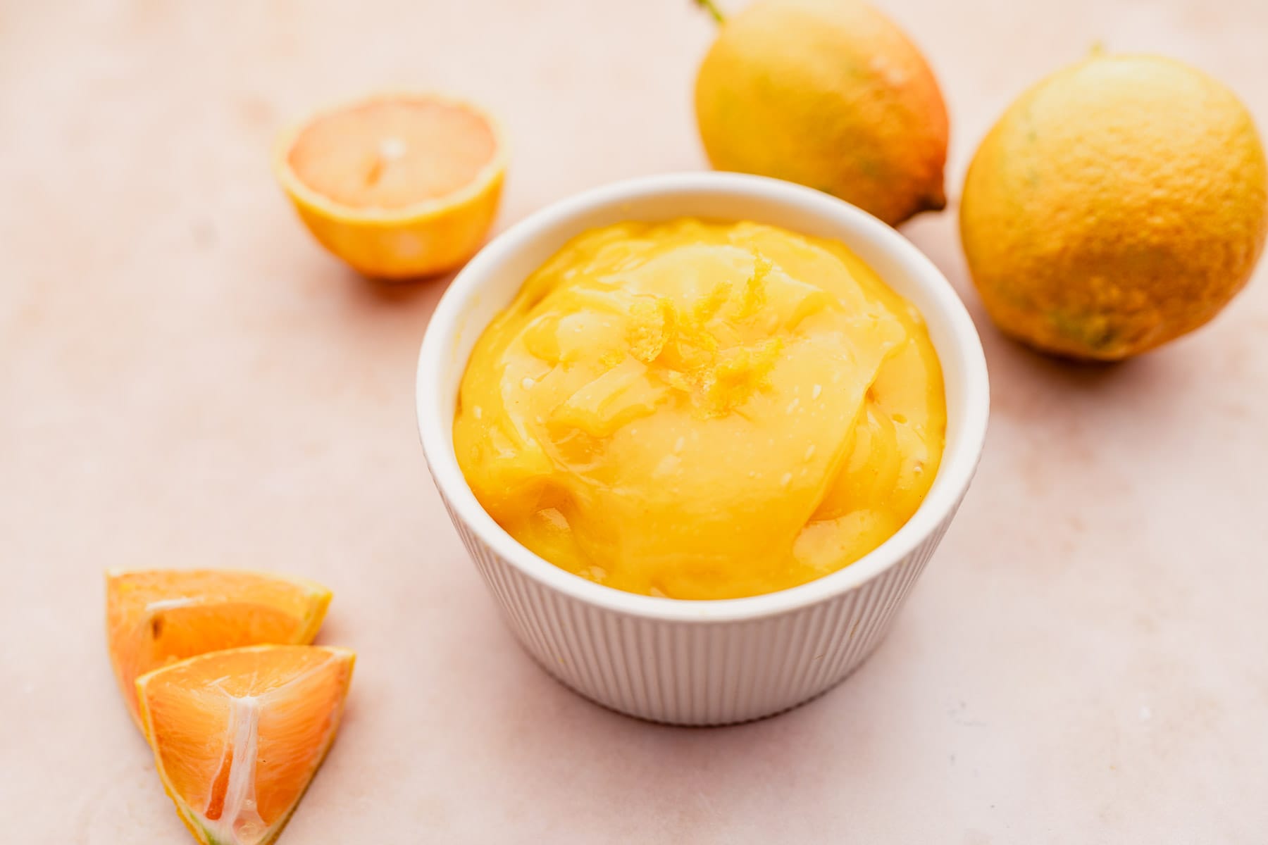 A white bowl with oranges and vegan lemon curd in it.