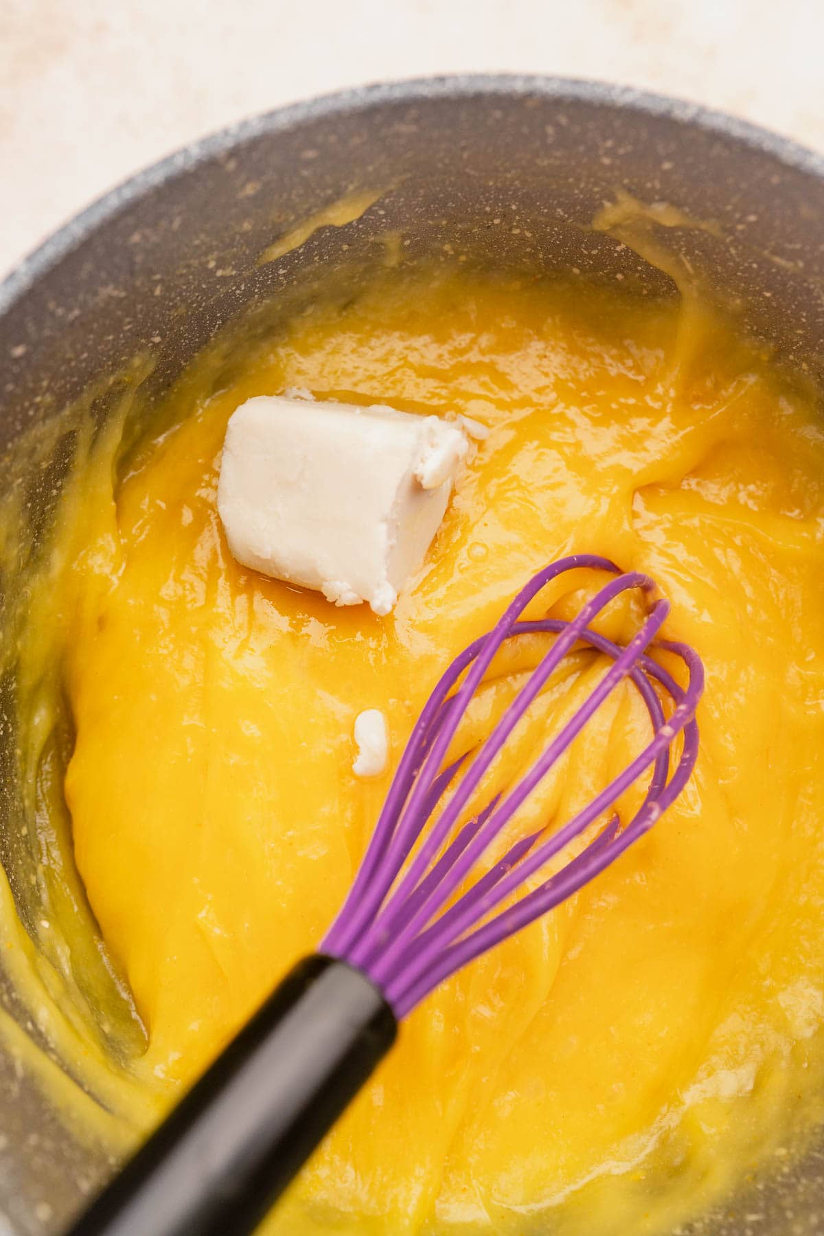 A vegan bowl of yellow batter with a whisk in it.
