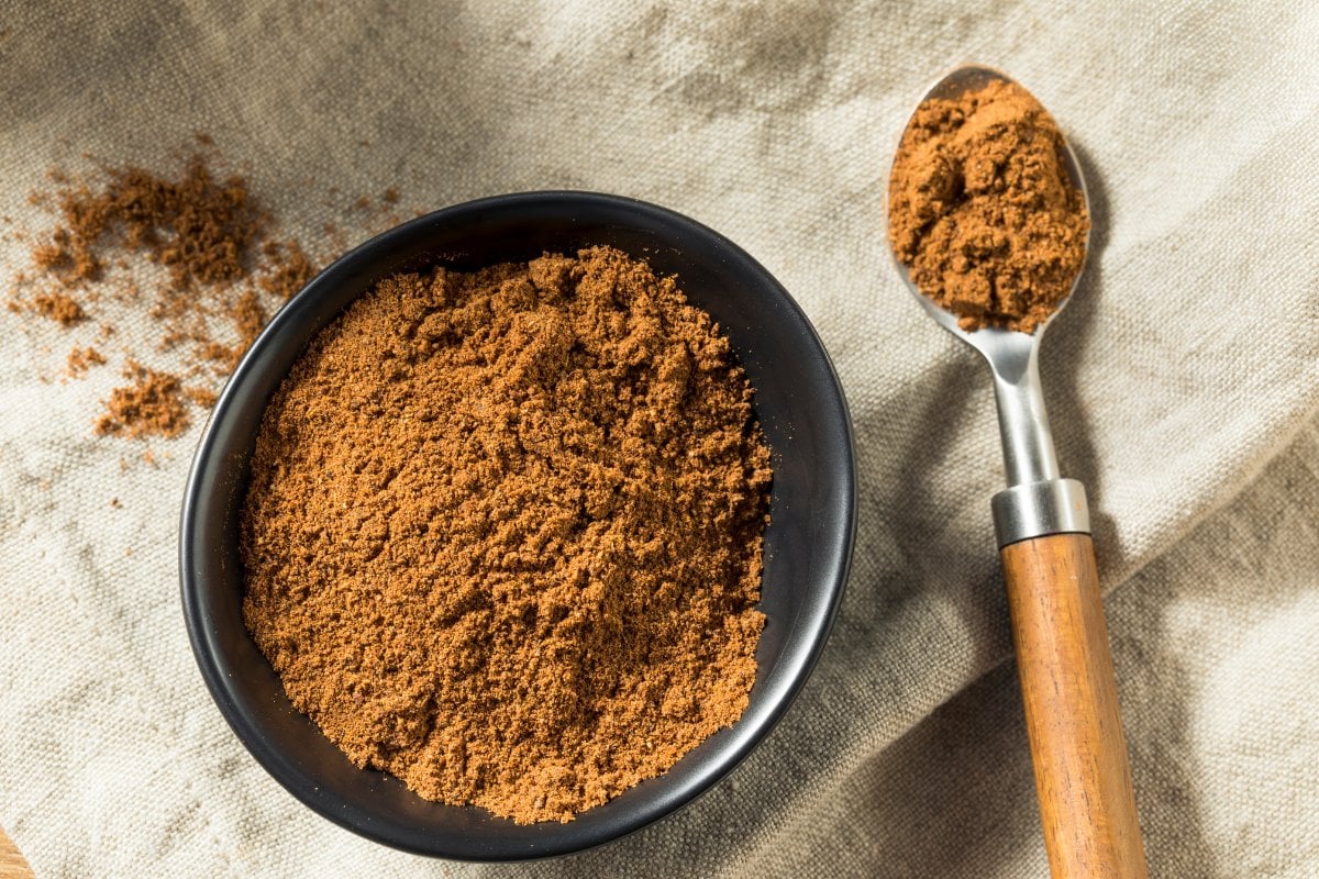 Cinnamon powder in a bowl next to a spoon.