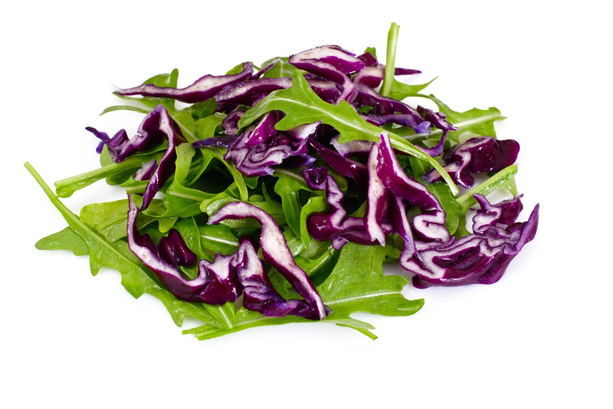 A pile of red cabbage and arugula on a white background.