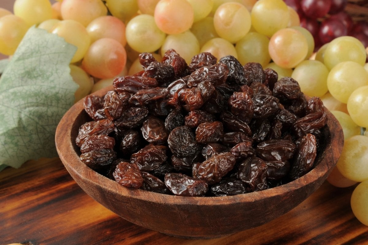 Raisins and grapes in a wooden bowl.