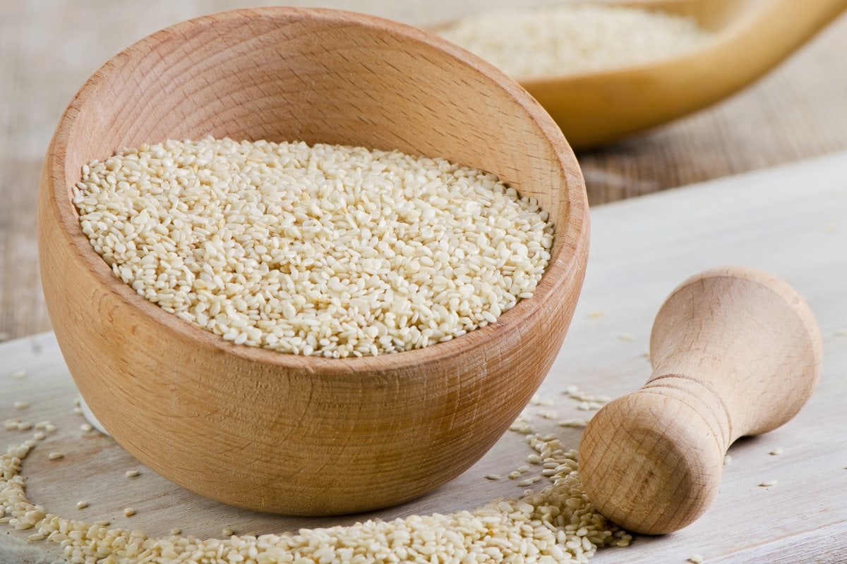 Sesame seeds in a wooden bowl on a wooden table.