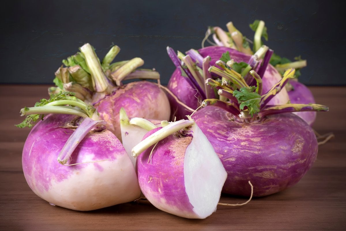 A bunch of purple turnips on a wooden table.