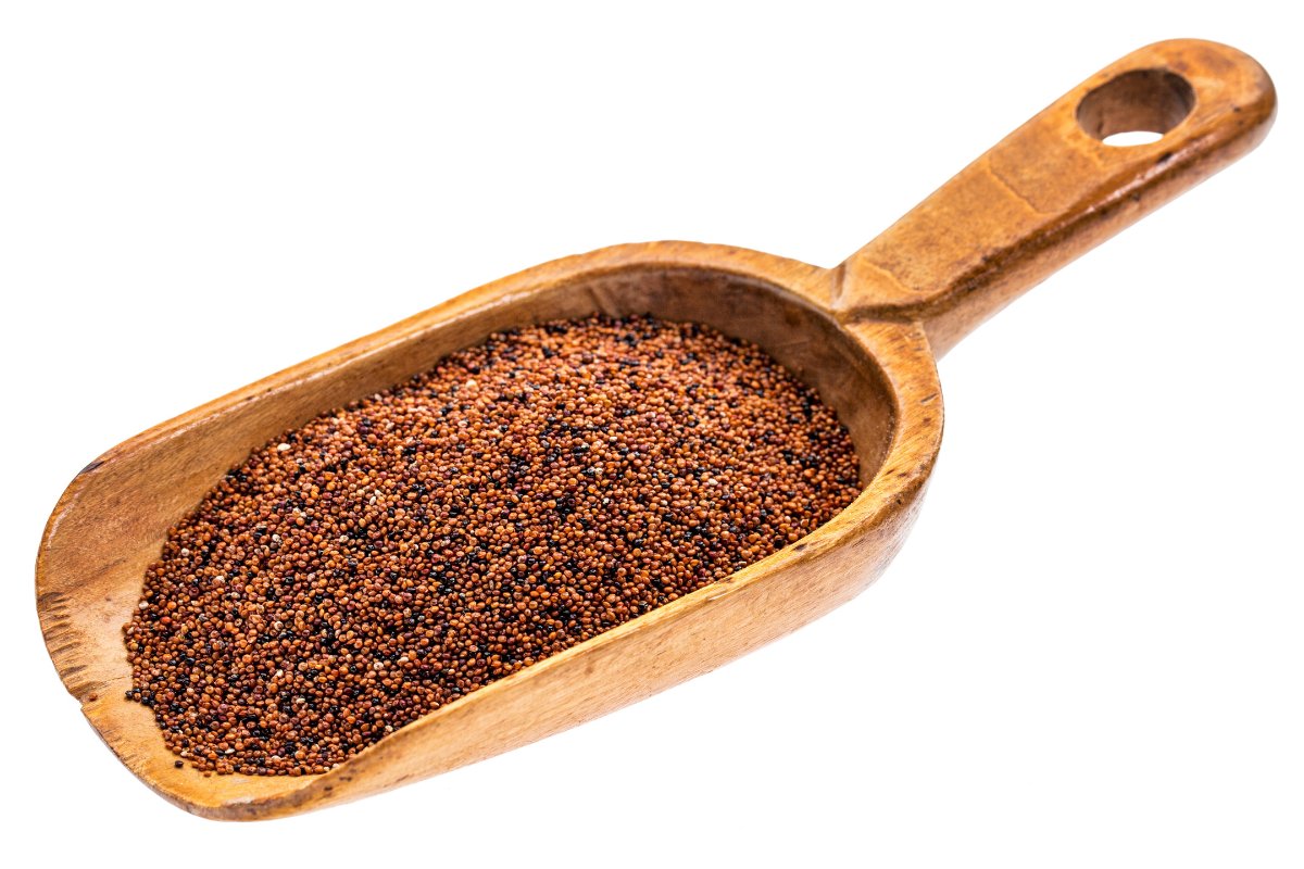 A wooden spoon filled with red chile powder on a white background.