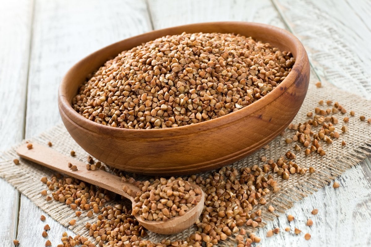 Fenugreek seeds in a wooden bowl on a wooden table.