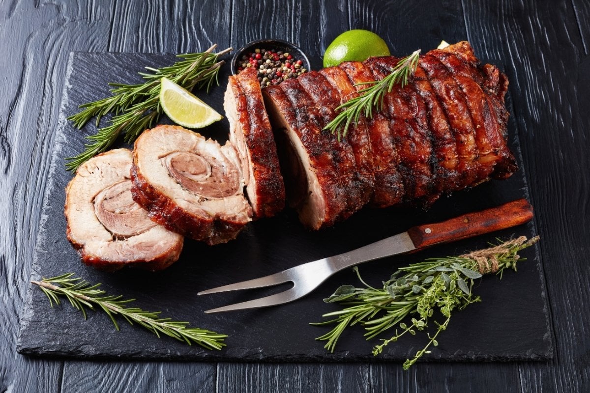 Grilled pork loin on a slate board with rosemary and lime.