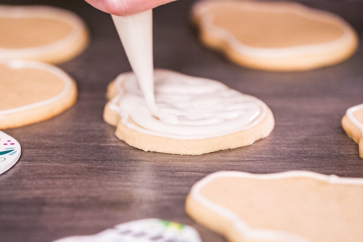 A person is icing some cookies with icing.