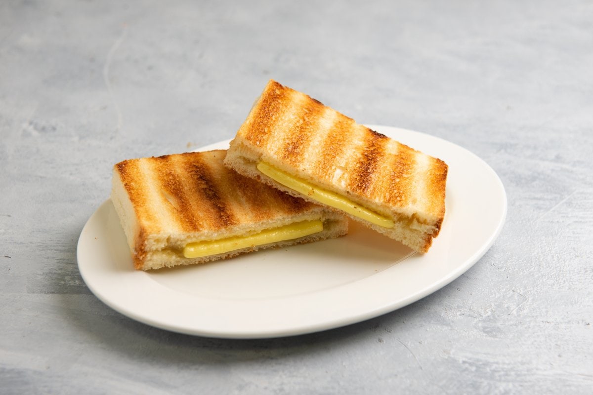 Two slices of grilled cheese sandwich on a plate.