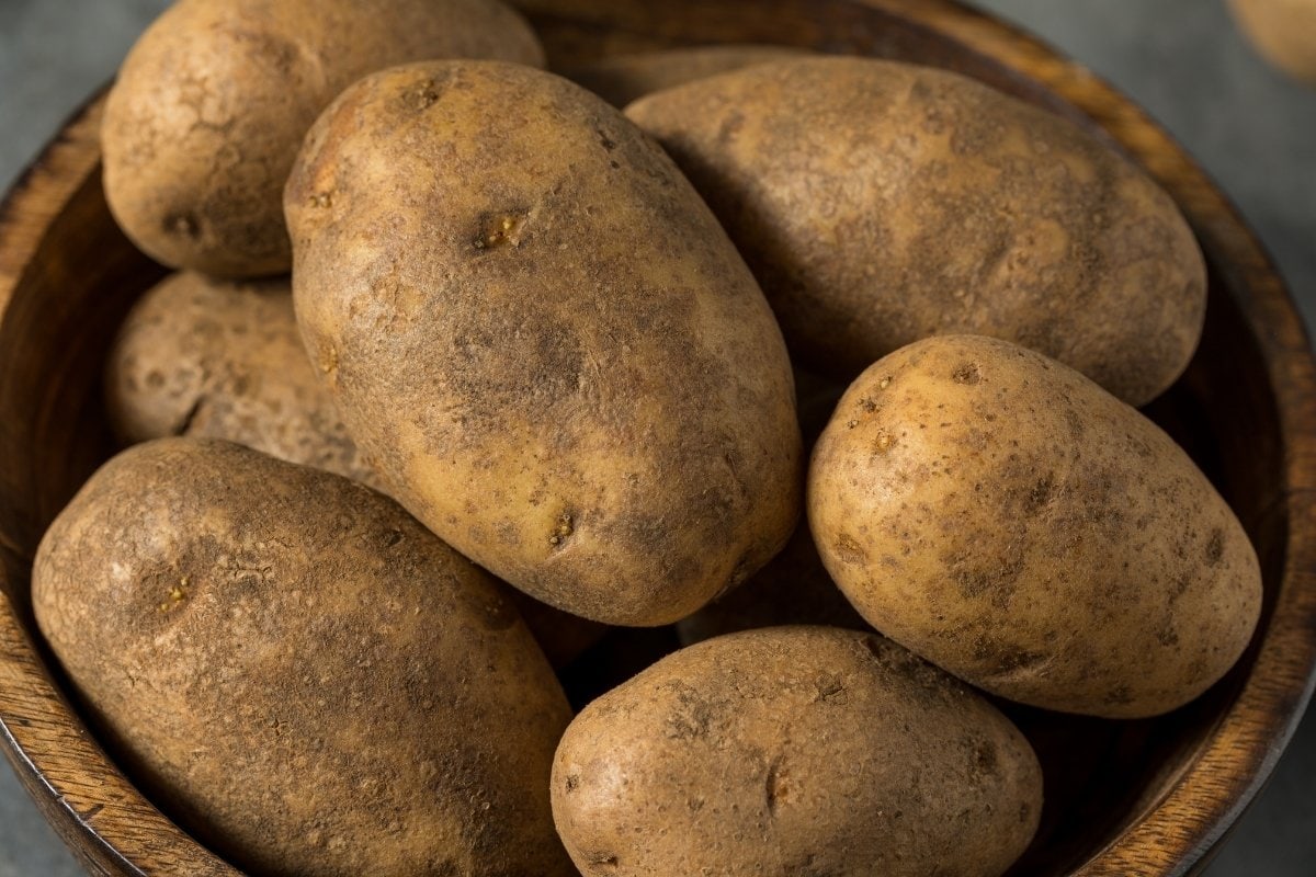 Potatoes in a wooden bowl on a grey background.