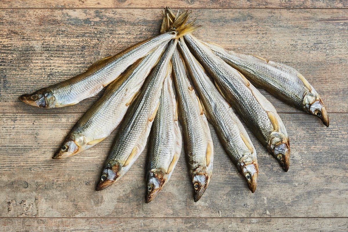A group of dried sardines on a wooden surface.